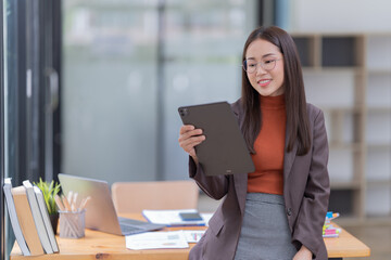 Sharing good business news. Attractive young businesswoman talking on the mobile phone and smiling while sitting at her working place in office and looking at laptop PC.