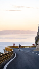 Road bike in mountains. 
racer in sport clothing, protective helmet and mirrored glasses riding...