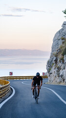Road bike in mountains. 
racer in sport clothing, protective helmet and mirrored glasses riding...