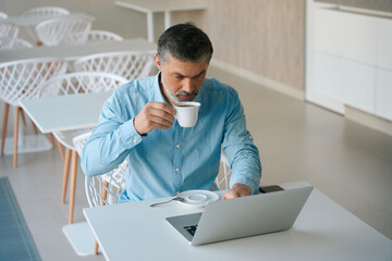 Adult man drinking coffee and working on computer