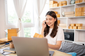 Online shopping business owner is talking on the phone with a customer to jot down the delivery address and delivery schedule, Packaging box Sell online, Work freelance.