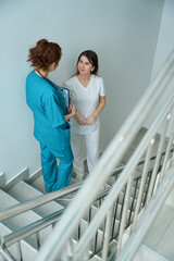 Doctor and nurse having conversation on stairway in clinic