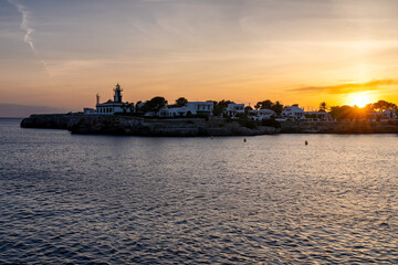 Fototapeta premium Landscape view of Cala Santandria with lighthouse at sunset Menorca, Spain.