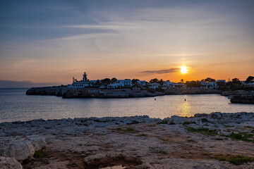 Obraz premium Landscape view of Cala Santandria with lighthouse at sunset Menorca, Spain.