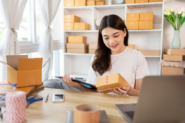 Fototapeta na wymiar Woman Writing Customer Details for Shipping in Home Office, Packing Box and Writing Customer Information for Efficient Shipping, E-Commerce and Online Selling Concept.