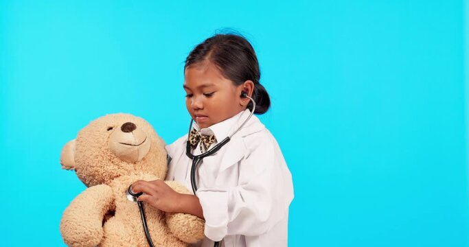 Child, doctor and teddy bear in a studio with medical check, stethoscope and patient analysis. Young girl, help and smile with blue background and healthcare, hospital and clinic coat for pretend fun