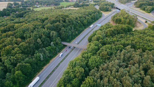 Aerial view of German highway autobahn . Drone shot of highway  among forest and green field. Cars fast speed moving on freeway.