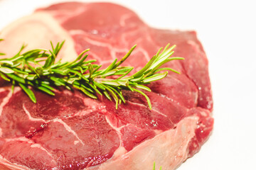 Fresh piece of meat large beef steak on the bone ossobuco with rosemary sprig.