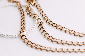 A necklace of white beads with chains of jewelry on a white aesthetic background.