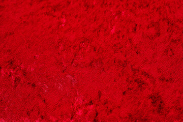Texture of red velor corduroy fabric with folds.