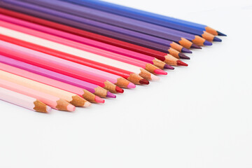 Fototapeta premium Multi-colored pencils lie on a white table, the violet range of colors