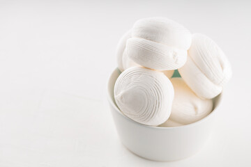 Sweet dessert white zephyr marshmallows in a bowl. Delicious zephyr marshmallows on a white background. Copy space