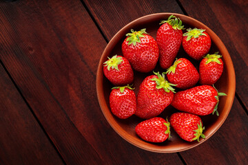 Fresh strawberries in plate on wooden table. Top view. Copy space
