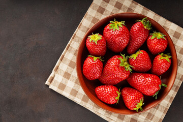 Ripe garden strawberry in bowl on linen napkin. Freshly picked strawberries on dark background. Copy space