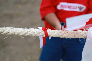 Indonesian kids celebrate Indonesia independence day with outdoor contest. Close up of tug - obrazy, fototapety, plakaty