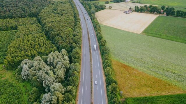 Aerial view of German highway autobahn . Drone shot of highway  among forest and green field. Cars fast speed moving on freeway.