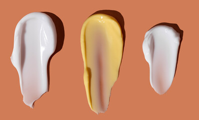 Yellow and white cosmetic smear of cream texture on orange background. Skin care. Copy space.