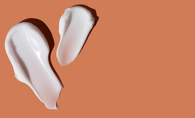 White cosmetic smear of cream texture on an orange background. Skin care. Copy space. Banner.