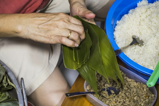 Photo of process for someone making Zongzi or traditional sticky rice dumplings that eaten during the Duanwu Festival like nasi ketan and minced meat. Dragon Boat Festival, Bakcang, Bacang.