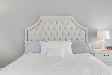 Beautiful bright calm traditional residential modern interior primary bedroom detail of headboard and bedding