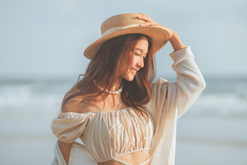 Summer beach vacation concept, Young asian woman with hat relaxing with her arms raised to her head...