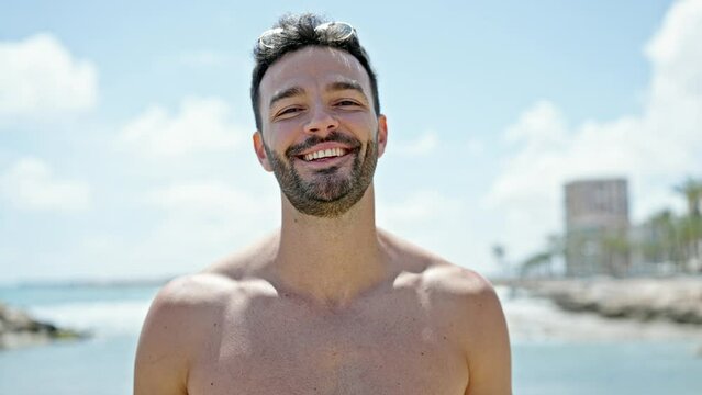 Young hispanic man tourist smiling confident shirtless at the beach