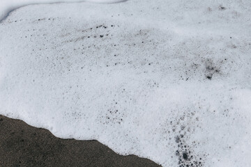 White sea foam on the beach. Beautiful texture of ocean waves