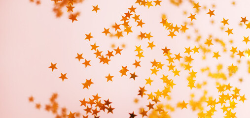 Banner of gold sequins and confetti in the shape of stars on a pink background