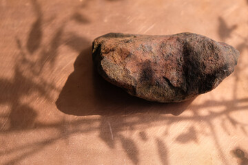 Ochre or Ocher stone on a copper surface. Red ochre. The Ocher mineral. Plant shadow. Sunlight. Copy space. - obrazy, fototapety, plakaty