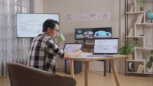 Side View Of Asian Male Drinking Coffee While Drawing New Car Design Concept On A Tablet In The Studio With Tv And Computers Display 3D Electric Car Model 
