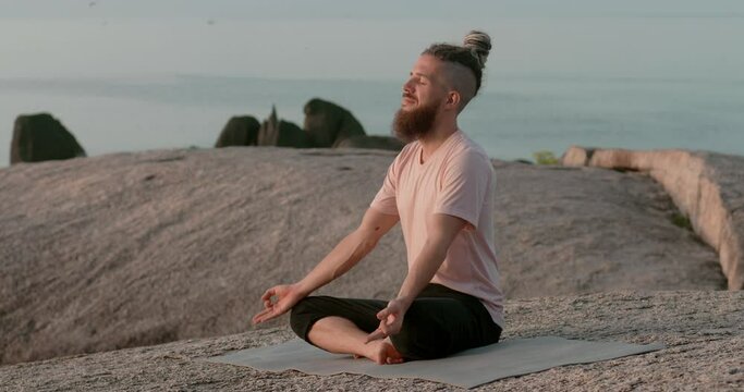 guy with shaved temples sits on stone the concept of spiritual growth. guy catches zen and comprehends spiritual growth.View of the sky at dawn guy meditates in the lotus position spiritual growth