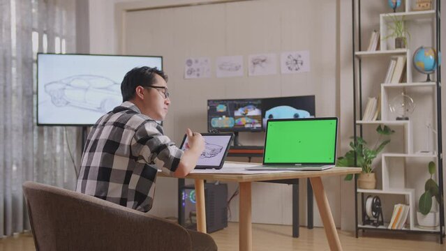 Side View Of Asian Male Thinking About Car Concept On Tablet Beside Green Screen Laptop Then Raising Index Finger In The Studio With Tv And Computers Display 3D Electric Car Model 
