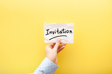 Invitation - card with text on paper note in hand on yellow background