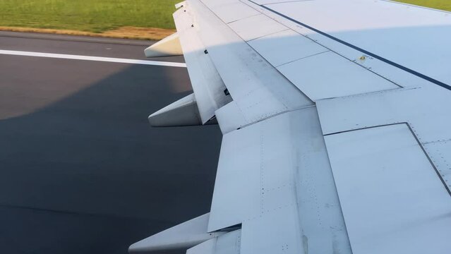 Travel video from the airplane window during takeoff. The aircraft wing and the runway through the passenger's eyes through the porthole on a clear sunny day. High quality 4k footage