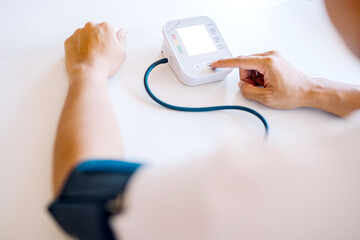 Monitoring patients' blood pressure using an upper arm blood pressure monitor in the clinic examination room.