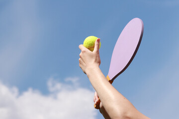 Play paddleball with a wooden racket against a blue sky. Beach tennis. A wooden paddle for playing...