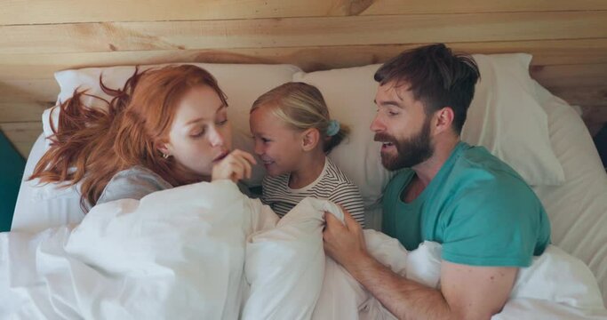 Happy, comfy and above of a family in bed for love, care or bonding together at night. Smile, talking and a mother, father and child in the bedroom with a blanket for comfort and to relax in a house