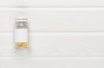 Plastic bottle with vitamins on wooden background, top view