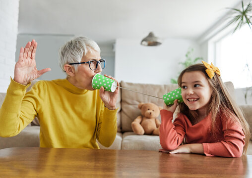 grandchild family child grandparent grandmother game playing granddaughter phone toy communication connection call string talk cup telephone voice message technology sound listen wire girl hobby
