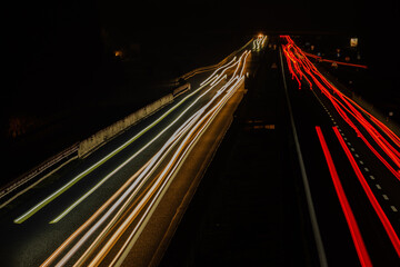 Fototapeta na wymiar Abstract image of night traffic lights on the road. Car light trails at night in curve asphalt road. Long exposure showing movement of cars from bridge or drone