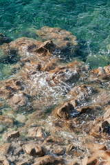 Waves on rocky beach, sea shore with waves crushing over the big rocks, summer sunny day