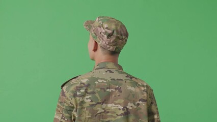 Close Up Of Back View Of Asian Man Soldier Looking Around While Standing In The Green Screen Background Studio
