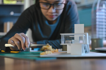 Architecture students diligently make house model building samples with paper architecture and...