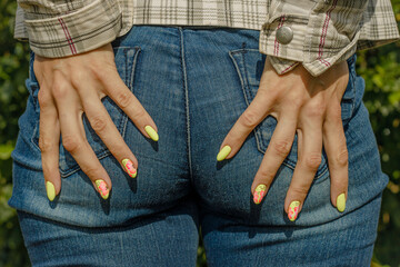A woman touches her bottom in jeans with her hands. A girl in jeans with a tight ass. Funny outdoor...