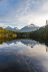 Fototapeta na wymiar sunrise over a calm lake with mountains and forest landscape