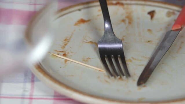 A person who, after eating, puts cutlery and a handkerchief on the dirty plate