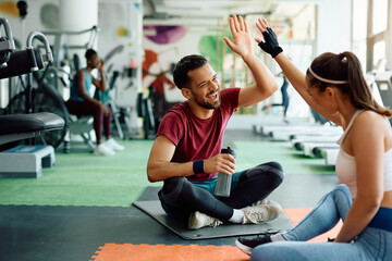 Happy athletic couple giving high five after finishing sports training in gym.
