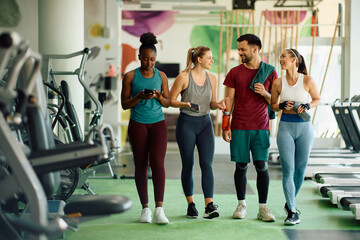 Happy athletic friends communicating after sports training in gym.