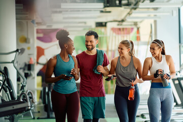 Multiracial group of happy friends talk after exercising in gym.