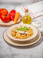 Fusilli pasta with minced meat, tomato sauce, cheese and basil